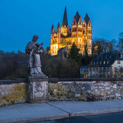 Deutschland, Hessen, Limburg an der Lahn, Statue des Johannes von Nepomuk auf der Lahnbrücke in der Abenddämmerung mit beleuchtetem Limburger Dom im Hintergrund - MHF00577