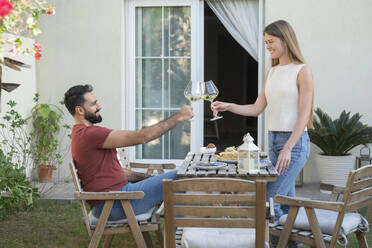 Smiling couple toasting wineglasses in garden - SVKF00070