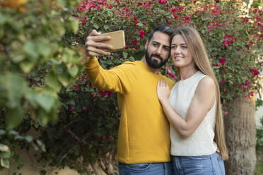 Mann macht Selfie mit Frau durch Smartphone im Hinterhof - SVKF00071