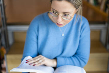 Young woman reading book on stairs - FBAF01969