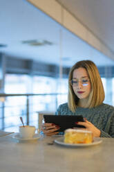 Junge Frau mit Tablet-PC am Tisch sitzend - FBAF01973