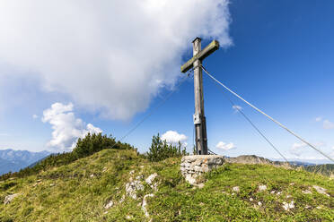 Blick auf das Brunstlkopf-Gipfelkreuz bei bewölktem Himmel an einem sonnigen Tag - FOF13085