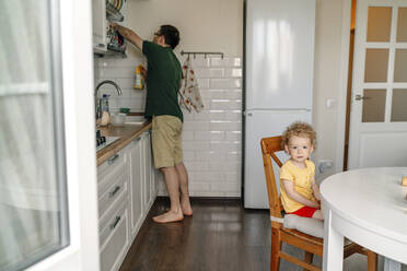 Girl sitting on chair with father in kitchen - OGF01134