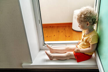 Nettes Mädchen sitzt an der Balkontür - OGF01142