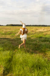 Young woman running on grass field - SSGF00545