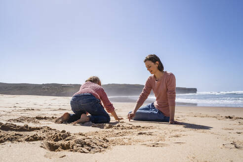 Mutter und Tochter schreiben auf Sand am Strand - DIGF17795