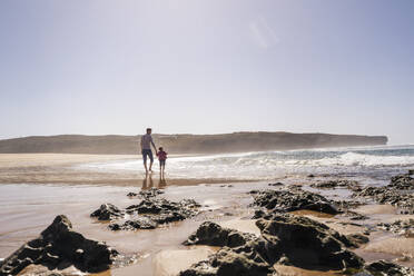 Vater und Tochter stehen am felsigen Strand - DIGF17806