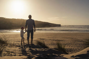 Vater und Tochter genießen den Sonnenuntergang am Strand - DIGF17812