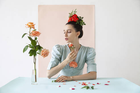 Young woman holding rose against pink backdrop - IYNF00123