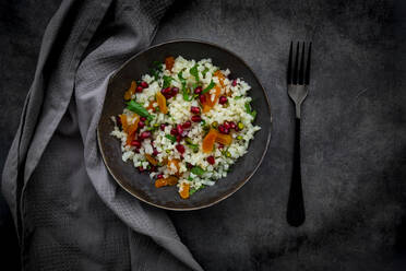 Studioaufnahme einer Schüssel Blumenkohlsalat mit Aprikose, Granatapfelkernen, Pistazien, Minze und Petersilie - LVF09228