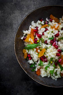 Studioaufnahme einer Schüssel Blumenkohlsalat mit Aprikose, Granatapfelkernen, Pistazien, Minze und Petersilie - LVF09229