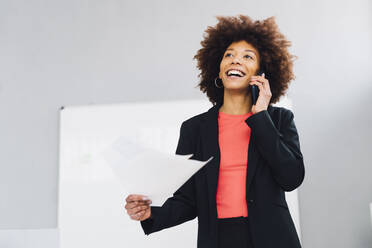 Happy businesswoman talking on mobile phone in office - GIOF15163