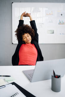 Businesswoman stretching at desk in office - GIOF15172