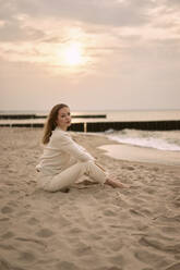 Beautiful woman sitting on sand at sunset - SSGF00572