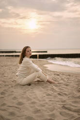 Schöne Frau sitzt auf Sand bei Sonnenuntergang - SSGF00572