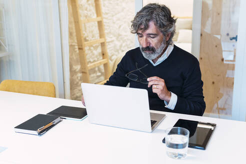 Freiberufler mit Brille und Laptop bei der Arbeit von zu Hause aus - PNAF03576