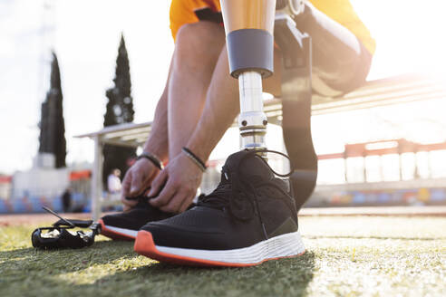 Hands of athlete tying shoelace on sunny day - JCCMF05997