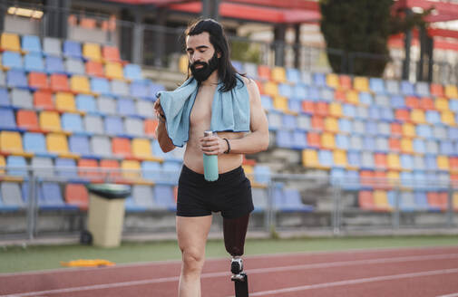 Mann mit Beinprothese, der eine Flasche hält, läuft auf einer Laufbahn - JCCMF06008