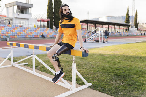 Mann mit Beinprothese sitzt auf Hürde - JCCMF06010