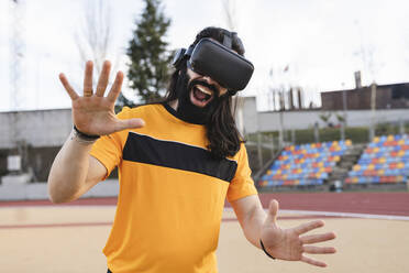 Bearded man wearing virtual reality simulator gesturing with mouth open - JCCMF06012