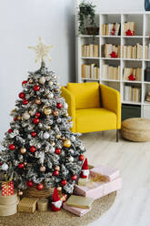 Decorated Christmas tree amidst gifts in living room at home - GIOF15203