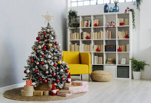 Geschmückter Weihnachtsbaum, umgeben von Geschenken im heimischen Wohnzimmer - GIOF15204
