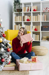 Happy woman with Christmas presents sitting at home - GIOF15226