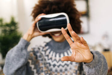 Woman gesturing with virtual reality simulator at home - GIOF15329