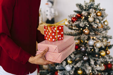 Frau trägt Weihnachtsgeschenke nach Hause - GIOF15340