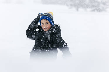 Lächelnder Junge mit Strickmütze, der Schnee wirft - JRFF05362