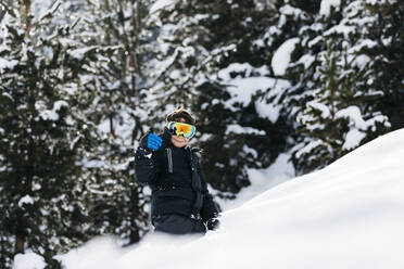 Lächelnder Junge mit Skibrille beim Gehen im Schnee - JRFF05365