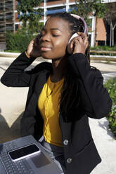Young woman wearing wireless headphones on sunny day - RFTF00190