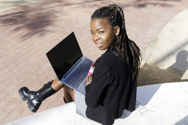 Junge Frau mit Laptop auf einem Betonsitz sitzend - RFTF00191