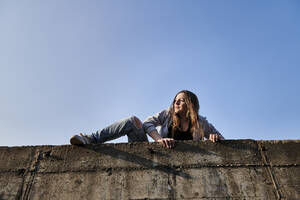 Junge Frau klettert über Betonwand - MMIF00284