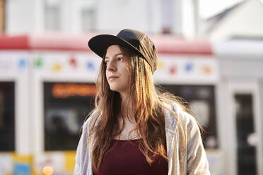 young woman with baseball cap standing in the city - MMIF00294