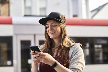 Junge Frau mit Smartphone in der Stadt - MMIF00297