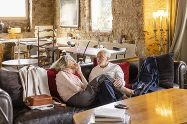 Älteres Paar, das auf einem Sofa in einem Boutique-Hotel sitzt und miteinander spricht - EIF03698
