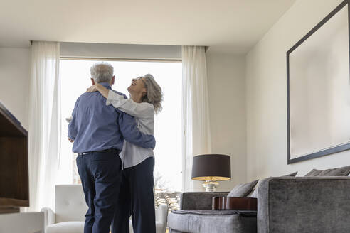 Happy senior couple dancing in living room at home - EIF03717