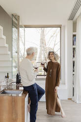 Älteres Paar mit Weingläsern in der Küche eines Hotelappartements - EIF03754