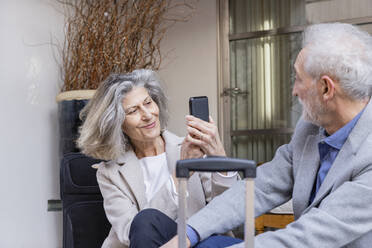 Lächelnde ältere Frau fotografiert Mann durch Handy - EIF03807