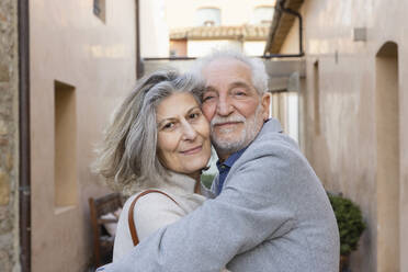 Ein glückliches älteres Paar umarmt sich im Innenhof eines Hotels - EIF03813