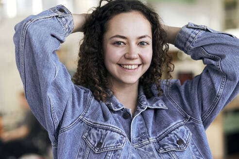 Smiling woman standing with hands behind head - SUF00690