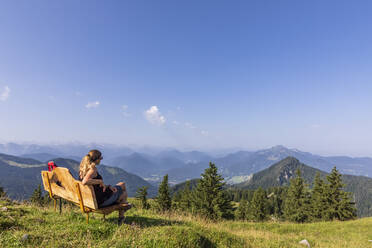 Deutschland, Bayern, Wanderin entspannt auf Bank am Gipfel des Fockensteins - FOF13100