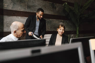 Männliche und weibliche Finanzberater diskutieren gemeinsam am Computerbildschirm am Arbeitsplatz - MASF29281