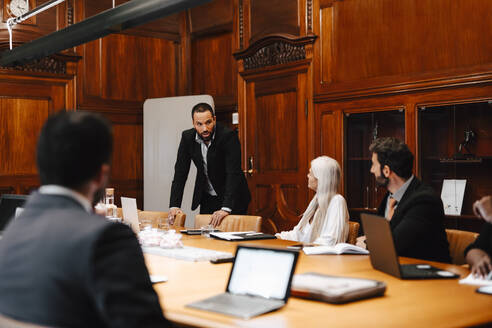 Geschäftsmann diskutiert mit Kollegen im Vorstandszimmer während einer Konferenzsitzung - MASF29354