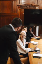 Colleagues looking at businessman discussing during meeting in board room - MASF29355