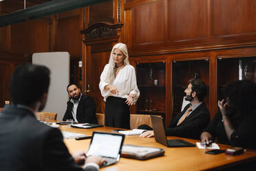 Selbstbewusste Geschäftsfrau diskutiert mit Anwälten im Sitzungssaal während einer Konferenzsitzung - MASF29362