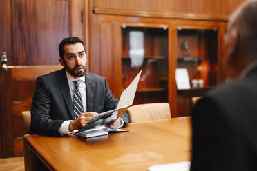 Ein selbstbewusster männlicher Finanzberater bespricht einen Vertrag mit einem älteren Geschäftsmann im Sitzungssaal - MASF29409