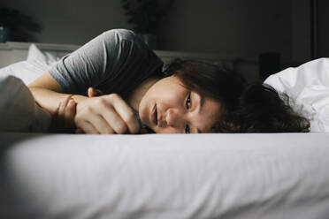 Tired woman suffering from mental health disorder lying on bed alone at home - MASF29444