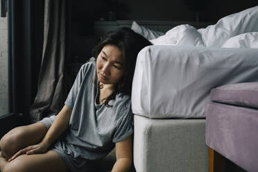 Traurige Frau mit psychischer Störung lehnt zu Hause auf dem Bett - MASF29445